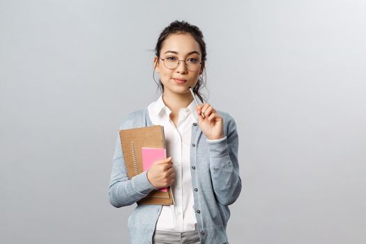 Education, teachers, university and schools concept. Smart and creative young woman, asian tutor preparing new interesting material for class, thinking-up ideas, touch lip with pencil, pondering.