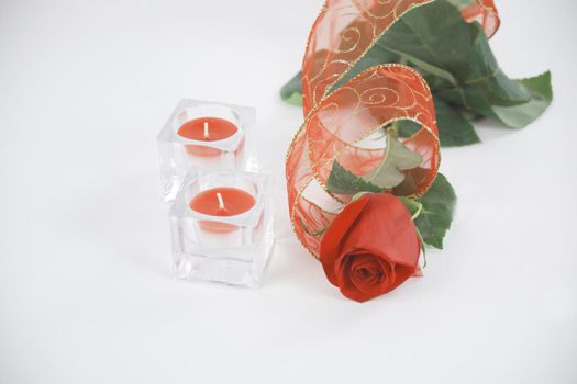 two candles and a red rose on a white background.photo with copy space.