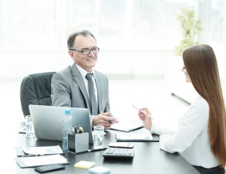 senior businessman talking to his young assistant at the Desk in the office