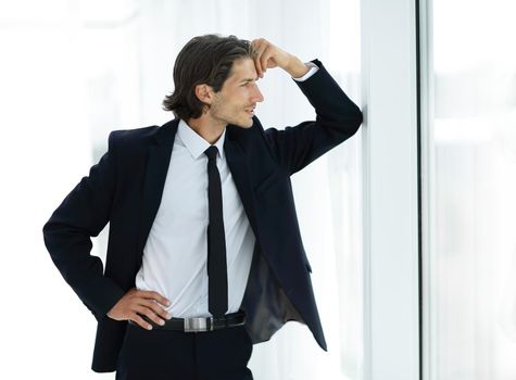 smiling businessman standing near window in office.the concept of perspective.