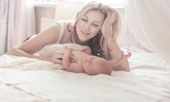 happy motherhood concept - happy mother and newborn baby in the bedroom