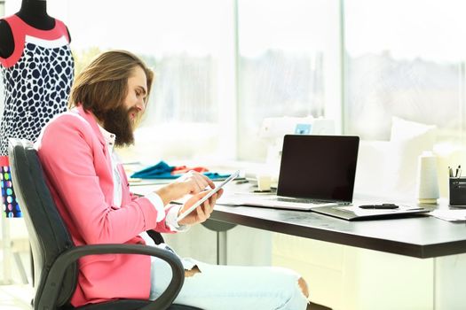 designer uses a digital tablet sitting in his Studio.