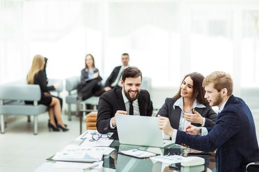 employees of the company work on laptop with information on the development of the company sitting behind a Desk in the office. the photo has a empty space for your text.