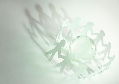 glass globe and a family of paper men on a green background. photo with copy space concept