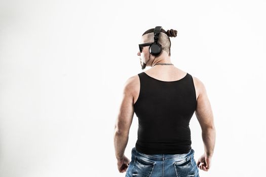 rear view - DJ - rapper with a stylish hairstyle with headphones on a light background.the photo has a empty space for your text
