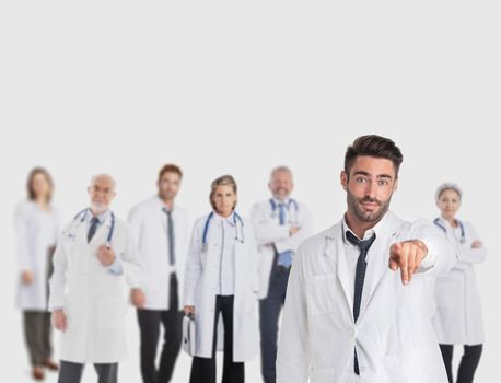 Medical doctor pointing at you, team of doctors on gray background, copy space for text