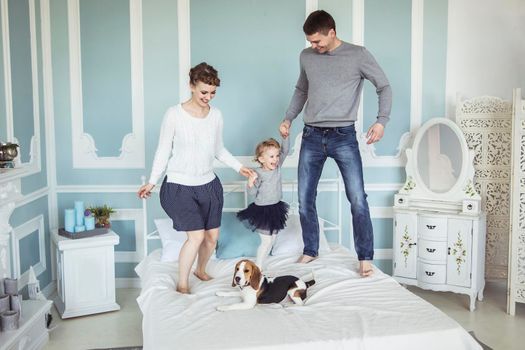 loving parents playing with baby daughter on bed in bedroom