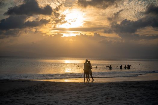 silhouette of romantic couple enjoying sunset on the beach during sunset dusk at radhasagar beach with the waves coming on the shore in havelock andaman india