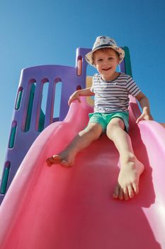 Child smiling playing on slider bar toy outdoor playground, happy preschool little kid having funny while playing on the playground equipment in the daytime in summer