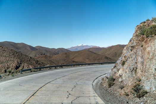 road in the mountains between the cliffs overlooking the snowy hills.