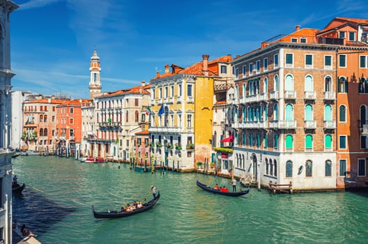 Venice, Italy, September 13, 2019: gondolier on gondola traditional boat sailing on water of Grand Canal waterway with Venetian architecture typical colorful buildings and bell tower background