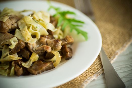 Homemade boiled noodles with meat and eggplant in a plate on a wooden table