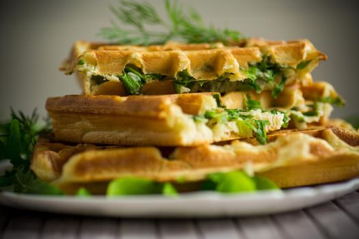 Homemade fried vegetable waffles with herbs inside on a wooden table