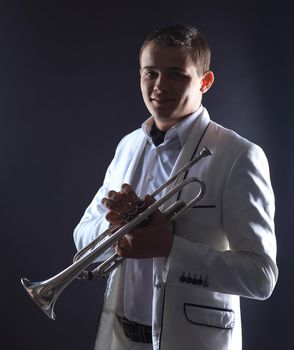 young man in a white suit with a trumpet.isolated on black background.