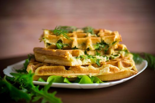 Homemade fried vegetable waffles with herbs inside on a wooden table