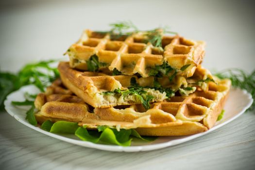 Homemade fried vegetable waffles with herbs inside on a wooden table