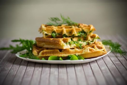 Homemade fried vegetable waffles with herbs inside on a wooden table