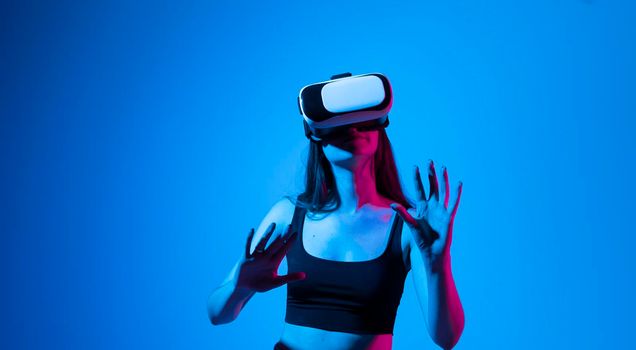 Brunette woman with VR headset touching something what she see in virtual world. Futuristic technology. Woman with glasses of virtual reality. Future technology concept