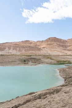 Sinkhole filled with turquoise water, near Dead Sea coastline. Hole formed when underground salt is dissolved by freshwater intrusion, due to continuing sea-level drop. . High quality photo