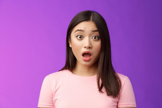 Close-up shocked gasping impressed asian brunette drop jaw stare camera impresssed, very surprised express full disbelief, speechless hearing astonishing news, stand purple background.