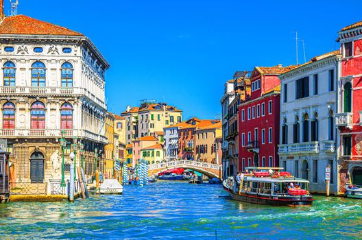 Venice, Italy, September 13, 2019: Grand Canal waterway across Cannaregio Canal with Palazzo Labia palace, Ponte delle Guglie bridge and vaporetto sailing in water, blue sky background in summer day