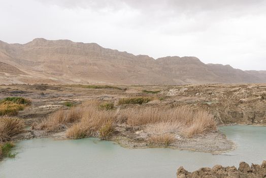 Sinkhole filled with turquoise water, near Dead Sea coastline. Hole formed when underground salt is dissolved by freshwater intrusion, due to continuing sea-level drop. . High quality photo