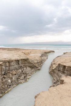 Sinkhole filled with turquoise water, near Dead Sea coastline. Hole formed when underground salt is dissolved by freshwater intrusion, due to continuing sea-level drop. . High quality photo