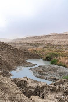 Sinkhole filled with turquoise water, near Dead Sea coastline. Hole formed when underground salt is dissolved by freshwater intrusion, due to continuing sea-level drop. . High quality photo