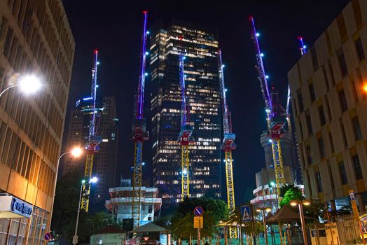 Tel Aviv, Israel - January 01, 2022: Construction site of high rise building in Tel Aviv. View Lifting cranes at night. High quality photo