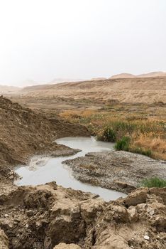 Sinkhole filled with turquoise water, near Dead Sea coastline. Hole formed when underground salt is dissolved by freshwater intrusion, due to continuing sea-level drop. . High quality photo