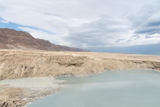 Sinkhole filled with turquoise water, near Dead Sea coastline. Hole formed when underground salt is dissolved by freshwater intrusion, due to continuing sea-level drop. . High quality photo