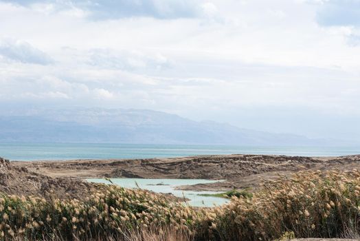 Sinkhole filled with turquoise water, near Dead Sea coastline. Hole formed when underground salt is dissolved by freshwater intrusion, due to continuing sea-level drop. . High quality photo