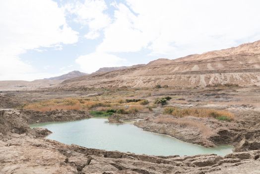 Sinkhole filled with turquoise water, near Dead Sea coastline. Hole formed when underground salt is dissolved by freshwater intrusion, due to continuing sea-level drop. . High quality photo