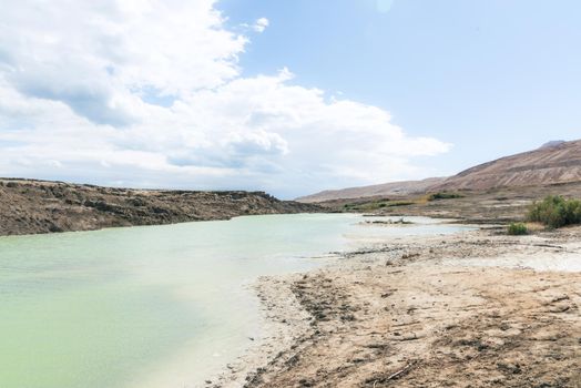 Sinkhole filled with turquoise water, near Dead Sea coastline. Hole formed when underground salt is dissolved by freshwater intrusion, due to continuing sea-level drop. . High quality photo