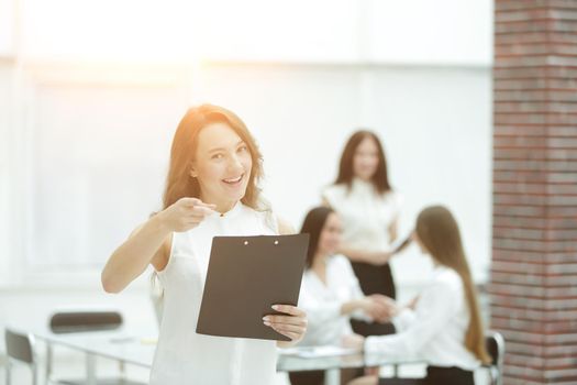 confident young business woman with clipboard on the background of business team.