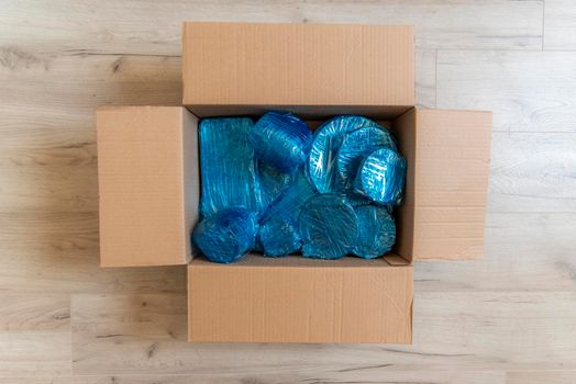 Glassware wrapped with blue wrapping nylon at the bottom of a cardboard box. High quality photo