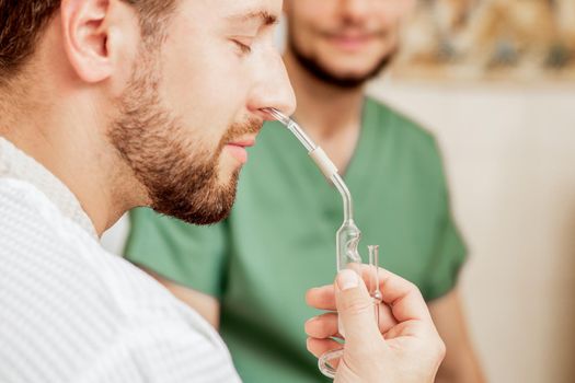 Man receiving nasal inhalation by essential oil in nose at spa.