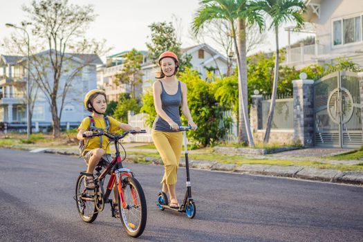 Active school kid boy and his mom in safety helmet riding a bike with backpack on sunny day. Happy child biking on way to school. Safe way for kids outdoors to school.