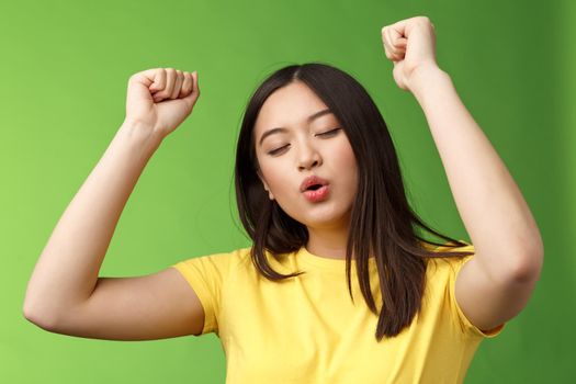 Close-up triumphing cute carefree asian woman having fun, dancing joyfully, forget all troubles moving rhythm music, fist pump victory, celebrating lucky news, close eyes relaxed. Copy space