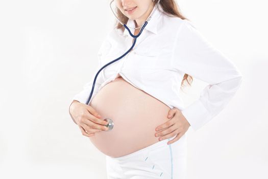 Pregnant woman listening through a stethoscope that makes her a child.isolated on white