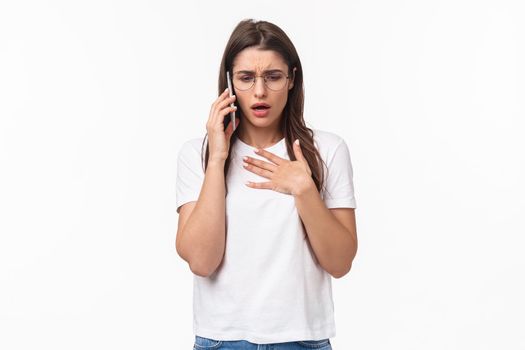 Communication, technology and lifestyle concept. Portrait of concerned and worried young woman express compassion and worry, calling sick friend asking if she okay, hold mobile near ear, touch heart.