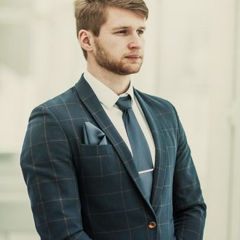newcomer businessman in a business suit stands near the window, hands folded in front of him .the photo has a empty space for your text