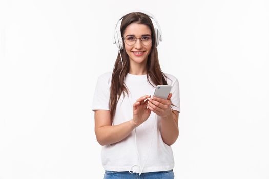 Technology, lifestyle and music concept. Portrait of charismatic, smiling young woman in headphones, listening songs playlist, bought premium account, enjoying favorite podcast, white background.