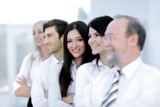 Dream team. Close-up of a business woman in selective focus looking at a camera with her colleagues in formal wear standing behind her in a row in blurry
