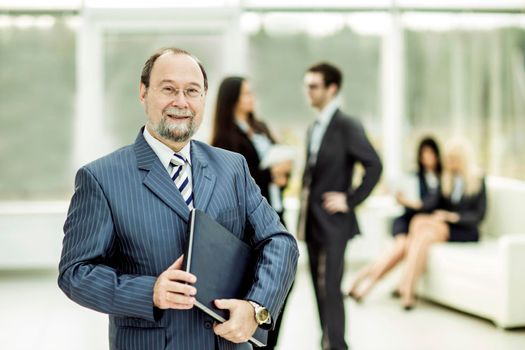 successful businessman with documents on the background of business team and office. the photo has a empty space for your text