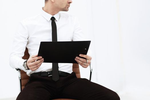 attentive businessman with clipboard sitting on office chair.