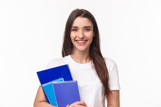 Education, university and studying concept. Close-up portrait of friendly joyful female student with books and paperworks smiling camera, waiting for friend near classes or campus, smiling happy.