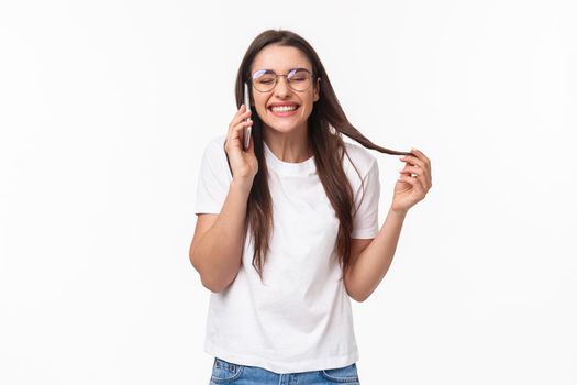 Communication, technology and lifestyle concept. Portrait of talkative funny and carefree, happy young caucasian woman talking on phone with friend, laughing over jokes, stand with mobile phone.