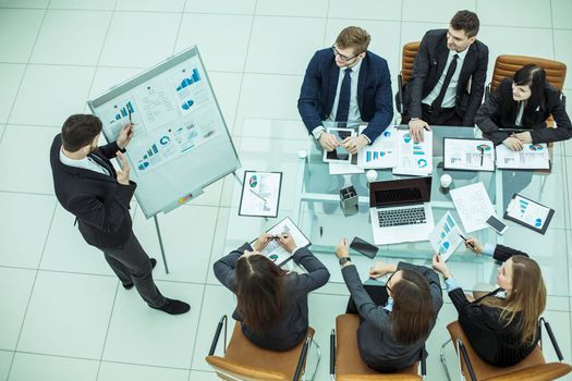 top view:businessman pointing the marker on the Board with financial schedules and business team sitting on workplace