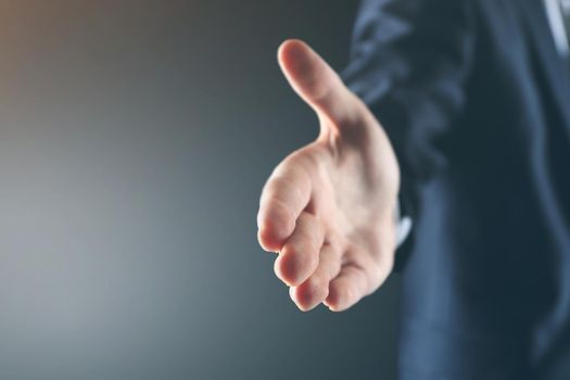 Business man with an open palm ready to strike a deal on a black background